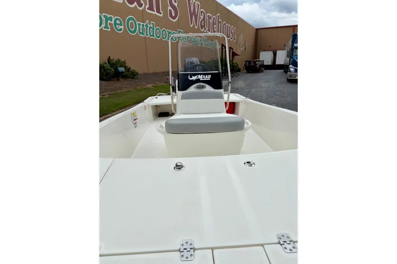 Slide: The Image of 2026 Mako Pro Skiff 15 CC boat displayed outdoors near a warehouse. - 1