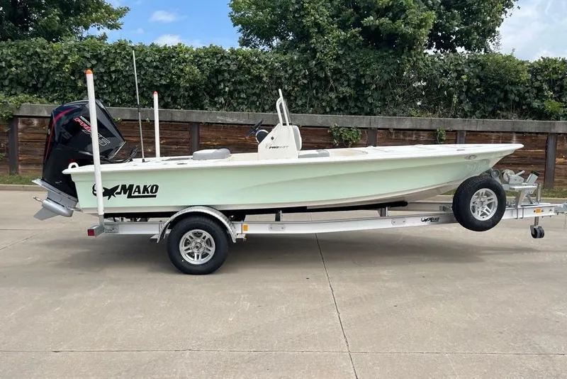 The Image of 2026 Mako 18 Pro Skiff on trailer, parked outdoors, featuring sleek design and powerful outboard motor. - 0