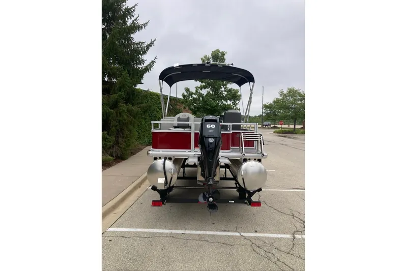 Slide: The Image of 2026 Sun Tracker Bass Buggy 18 DLX pontoon boat with outboard motor in parking lot. - 9