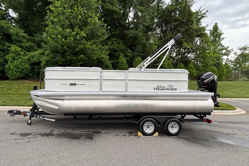 The Image of 2026 Sun Tracker Party Barge 20 DLX pontoon boat on trailer, parked outdoors. - 0