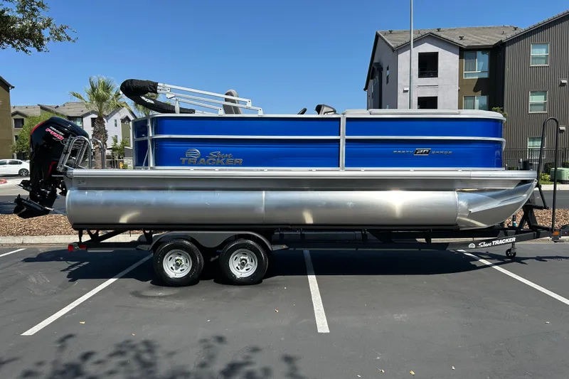 The Image of 2026 Sun Tracker Party Barge 20 DLX pontoon boat on trailer in parking lot. - 0