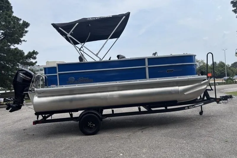 Slide: The Image of 2026 Sun Tracker Party Barge 18 DLX pontoon boat on trailer, blue and silver design. - 8