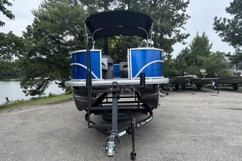 Slide: The Image of 2026 Sun Tracker Party Barge 18 DLX pontoon boat on trailer, parked near a lake. - 2