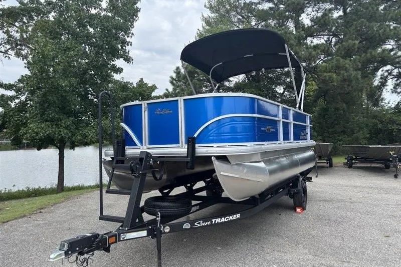 Slide: The Image of 2026 Sun Tracker Party Barge 18 DLX pontoon boat on trailer by a lake. - 3