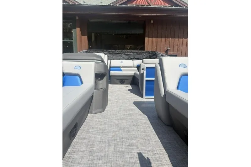 Slide: The Image of 2026 Sun Tracker Party Barge 20 DLX interior with gray and blue seating, docked near a wooden structure. - 5