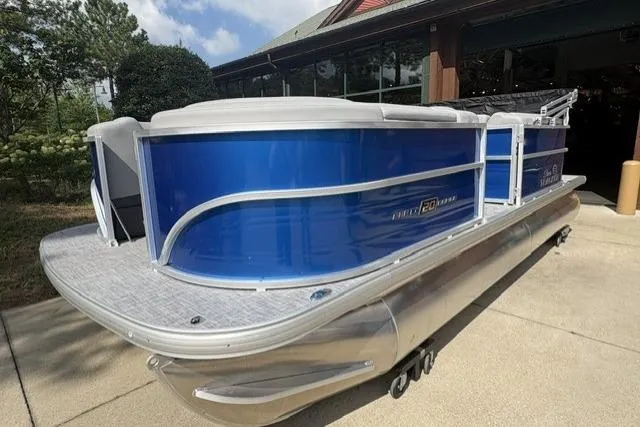 Slide: The Image of 2026 Sun Tracker Party Barge 20 DLX pontoon boat with sleek blue exterior, docked outdoors. - 2