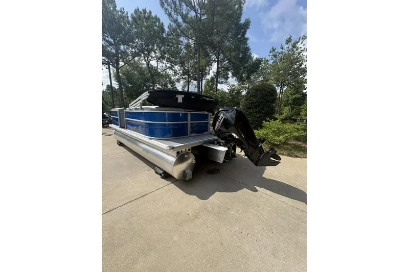 Slide: The Image of 2026 Sun Tracker Party Barge 20 DLX pontoon boat on a driveway, surrounded by trees. - 4