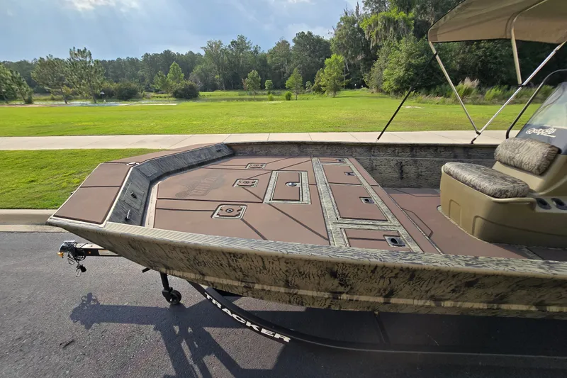 Slide: The Image of 2026 Tracker Grizzly 2072 CC boat on trailer, parked near lush green landscape. - 5