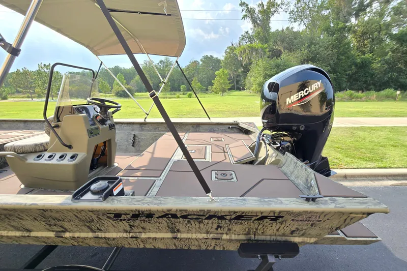 Slide: The Image of 2026 Tracker Grizzly 2072 CC boat with Mercury engine, parked outdoors under a canopy. - 8