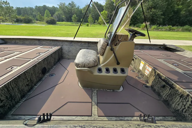 Slide: The Image of 2026 Tracker Grizzly 2072 CC boat interior with console and seating, surrounded by lush greenery. - 4