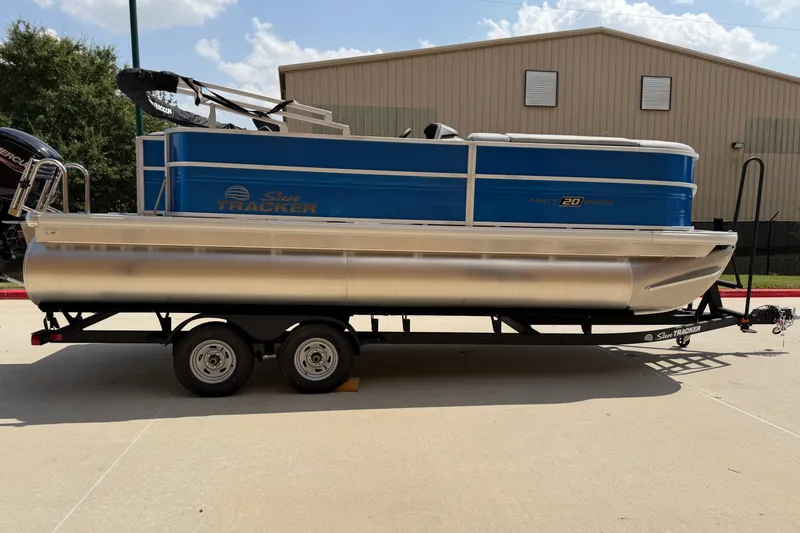 The Image of 2026 Sun Tracker Party Barge 20 DLX pontoon boat on trailer, parked outdoors. - 0