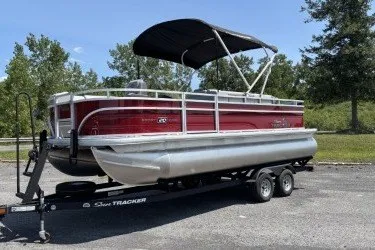 The Image of 2026 Sun Tracker SportFish 20 DLX pontoon boat on trailer, parked outdoors. - 0