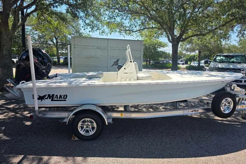 The Image of 2026 Mako 18 Pro Skiff boat on trailer, parked outdoors under trees. - 0