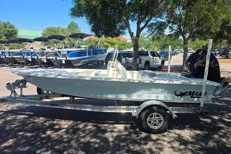 Slide: The Image of 2026 Mako 18 Pro Skiff boat on trailer, parked under trees in a lot. - 3