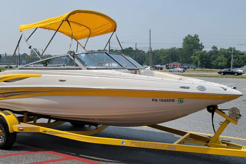 The Image of 2007 Crownline 19 SS boat with yellow accents and canopy on a trailer. - 1