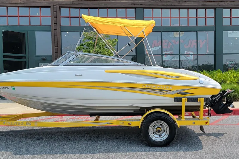 Slide: The Image of 2007 Crownline 19 SS boat with yellow accents on a trailer, parked outdoors. - 4