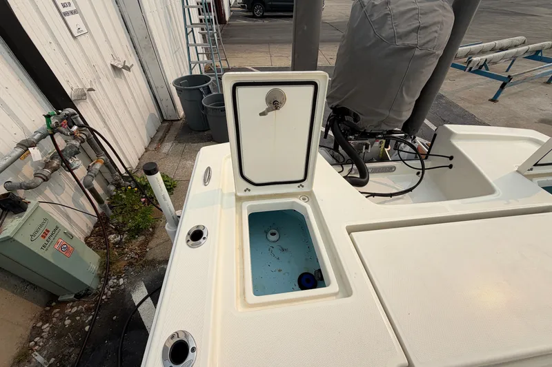 Slide: The Image of 2024 Pathfinder 2200 TRS boat with open storage compartment, docked near utility area. - 19