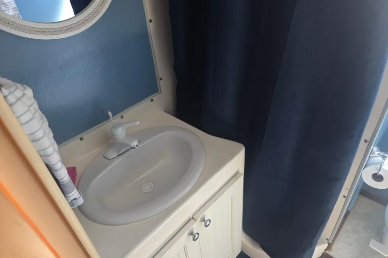 Slide: The Image of 1973 River Queen Star Stream bathroom with sink, mirror, and blue shower curtain. - 20