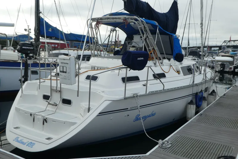 Slide: The Image of 1992 Hunter Passage 42 sailboat docked at marina, featuring white hull and blue canopy. - 0