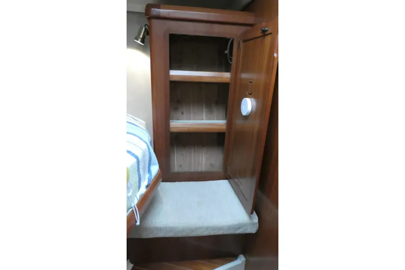 Slide: The Image of 1992 Hunter Passage 42 yacht interior with open wooden cabinet and cozy bedding. - 32