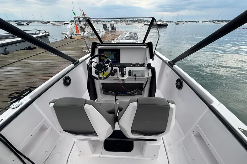 Slide: The Image of 2022 Axopar 22 T-Top boat interior with dual seats and steering console, docked by the water. - 8