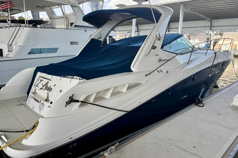 Slide: The Image of 2008 Sea Ray Sundancer 330 yacht docked, featuring sleek design and blue cover. - 2