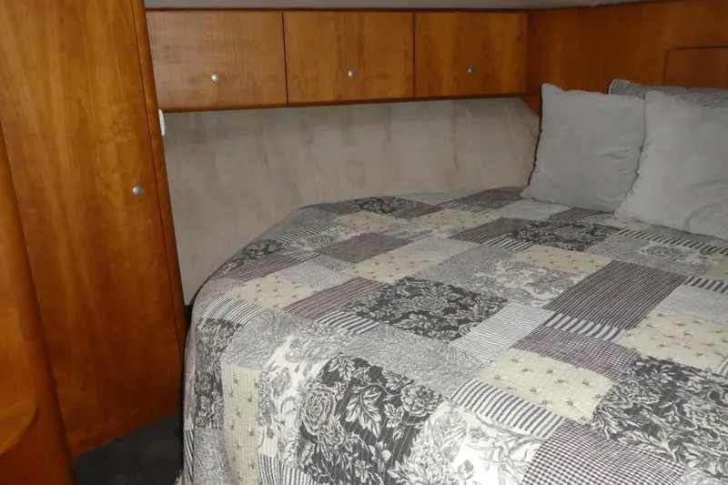 Slide: The Image of 1997 Silverton 41 Convertible cabin with quilted bedspread and wooden cabinetry. - 12