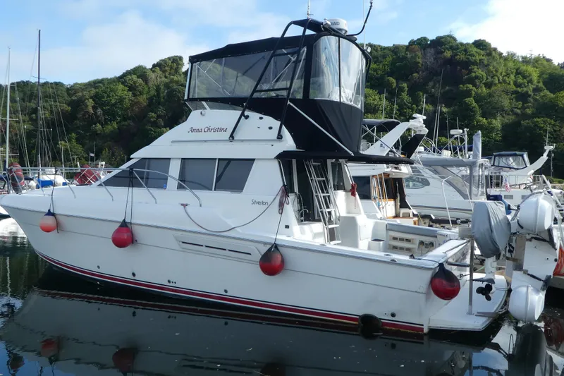 Slide: The Image of 1997 Silverton 41 Convertible yacht docked in a marina, surrounded by lush greenery. - 2