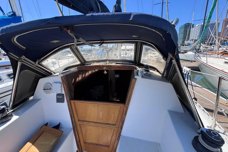 Slide: The Image of 1984 Islander 28 sailboat cockpit with wooden hatch, docked in a marina. - 23