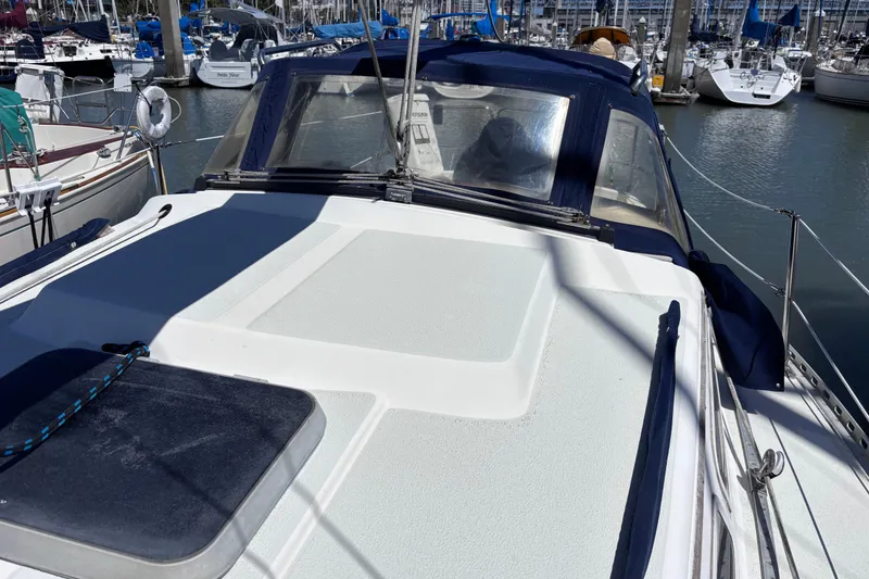 Slide: The Image of 1984 Islander 28 sailboat docked in marina, featuring a clean deck and blue canopy. - 25