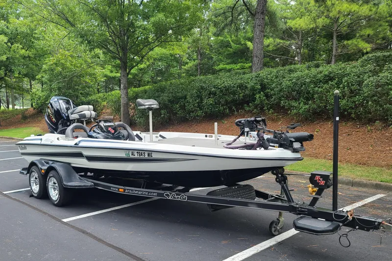 Slide: The Image of 2012 Bass Cat Cougar FTD boat on trailer in a wooded parking area. - 5