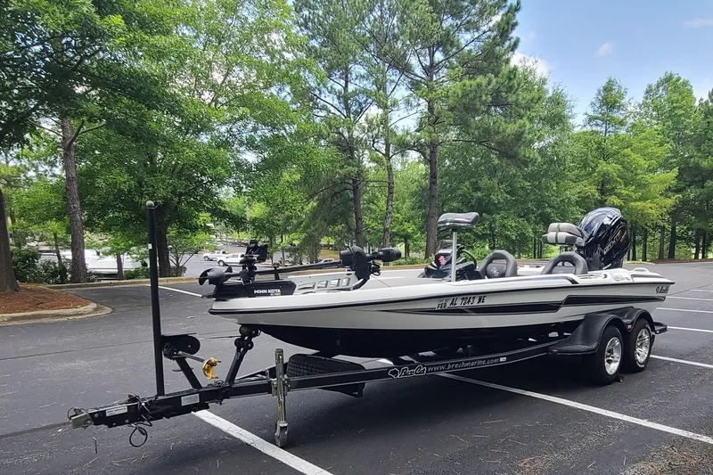 Slide: The Image of 2012 Bass Cat Cougar FTD boat on trailer in a wooded parking area. - 6