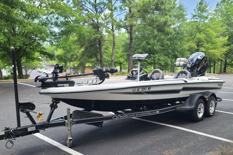 Slide: The Image of 2012 Bass Cat Cougar FTD boat on trailer in a wooded parking area. - 2