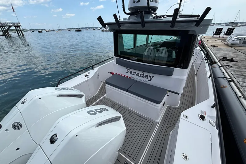 Slide: The Image of 2021 Axopar 28 Cabin boat docked, featuring twin outboard engines and sleek design. - 6