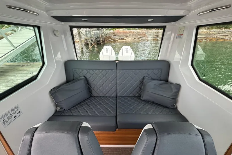 Slide: The Image of Interior of 2021 Axopar 28 Cabin boat with cushioned seating and scenic water view. - 16