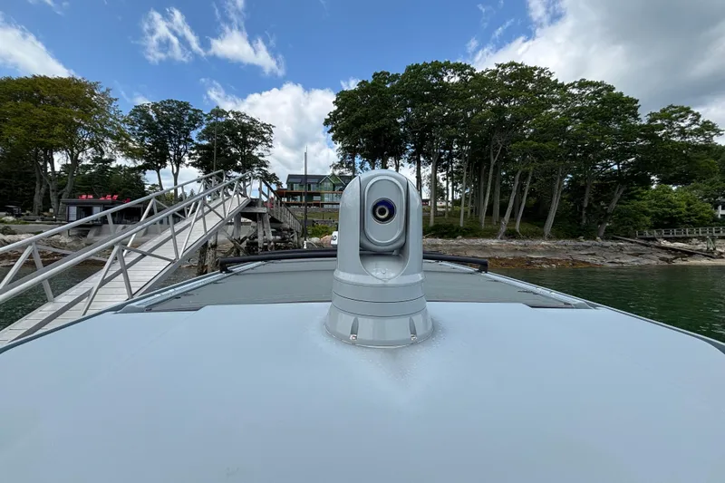 Slide: The Image of 2021 Axopar 28 Cabin boat docked near a scenic shoreline with trees and a wooden pier. - 23