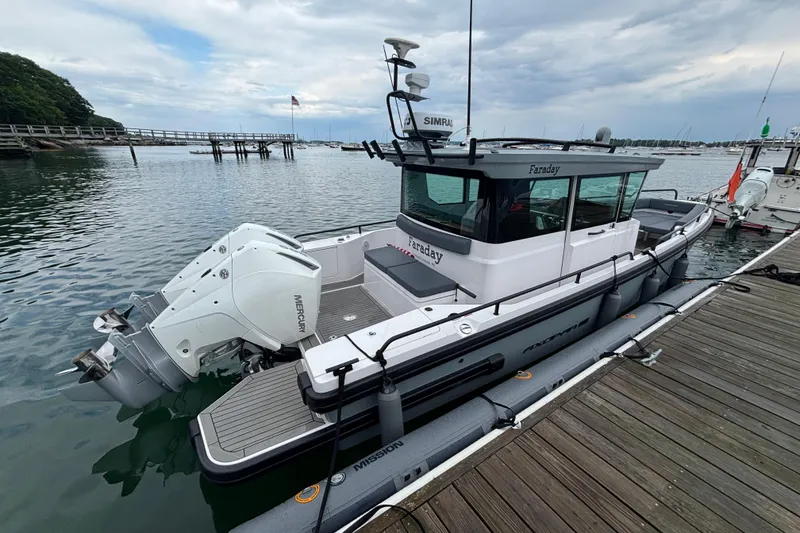 Slide: The Image of 2021 Axopar 28 Cabin boat docked, featuring twin Mercury outboard engines. - 1