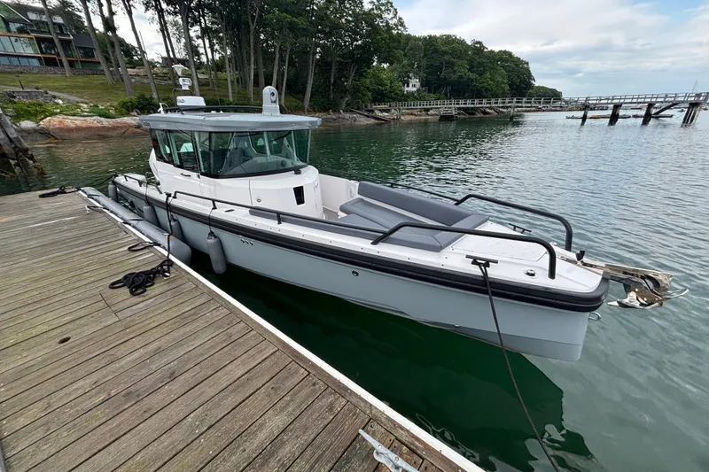 Slide: The Image of 2021 Axopar 28 Cabin boat docked by a scenic waterfront. - 2