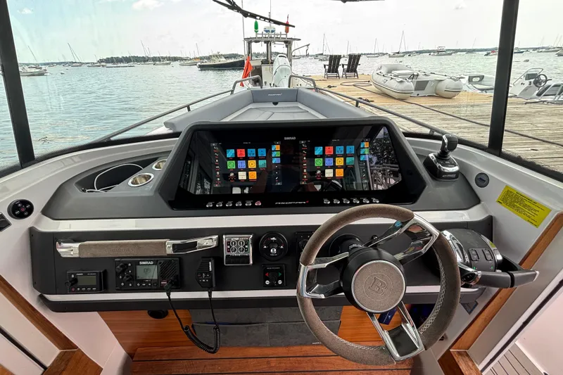Slide: The Image of 2021 Axopar 28 Cabin helm with advanced navigation system and scenic marina view. - 12