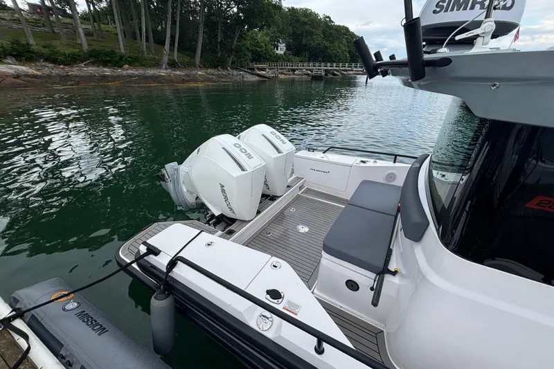 Slide: The Image of 2021 Axopar 28 Cabin boat with twin Mercury engines docked by a scenic shoreline. - 3