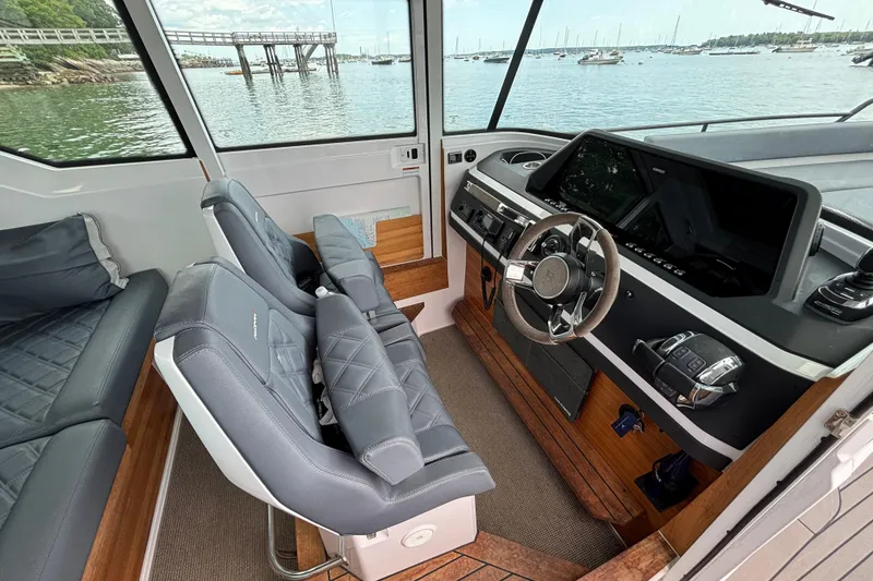 Slide: The Image of Interior of 2021 Axopar 28 Cabin boat with modern helm and seating, overlooking marina. - 15