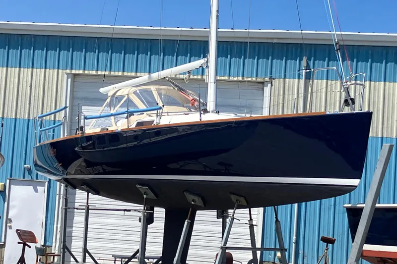 Slide: The Image of 2006 J Boats J/100 sailboat on stands, blue hull, near blue warehouse. - 2