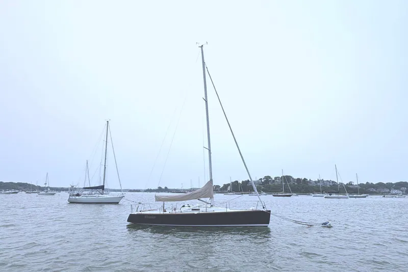 Slide: The Image of A 2006 J/100 sailboat is anchored in calm waters, surrounded by other boats. - 11