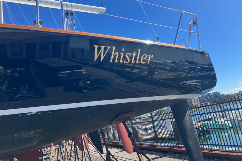 Slide: The Image of 2006 J Boats J/100 sailboat named "Whistler" docked at a marina under clear blue skies. - 8