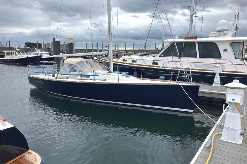 The Image of 2006 J Boats J/100 sailboat docked at a marina under cloudy skies. - 0