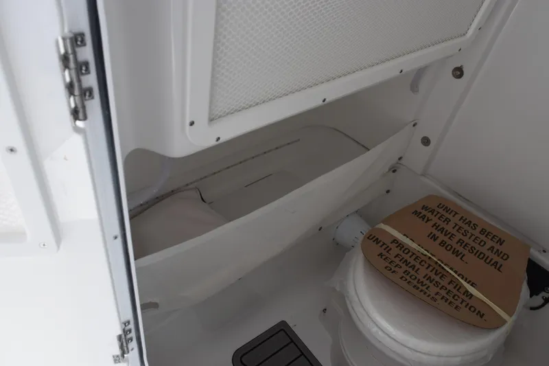 Slide: The Image of Interior of 2027 Sea Hunt Ultra 275 SE boat, featuring a compact marine toilet. - 15