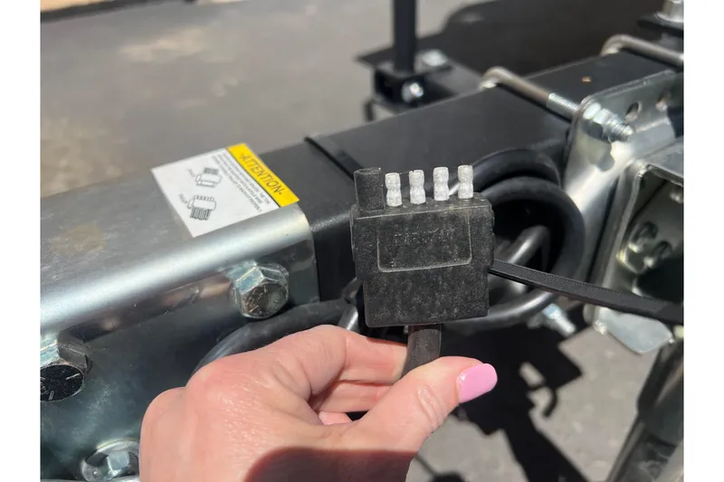 Slide: The Image of Close-up of a hand holding a trailer connector for a 2026 Sea-Doo Switch Cruise 21. - 4