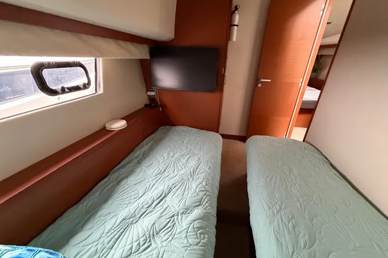 Slide: The Image of Twin beds in a 2012 Prestige 500S yacht cabin with a window and TV. - 41