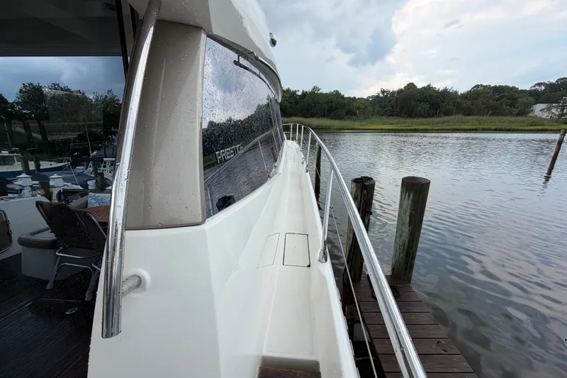 Slide: The Image of 2012 Prestige 500S yacht docked by a serene waterfront with lush greenery. - 85