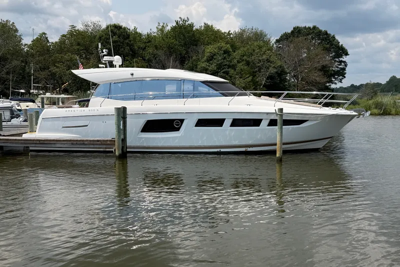Slide: The Image of 2012 Prestige 500S yacht docked on a calm river, surrounded by lush greenery. - 2